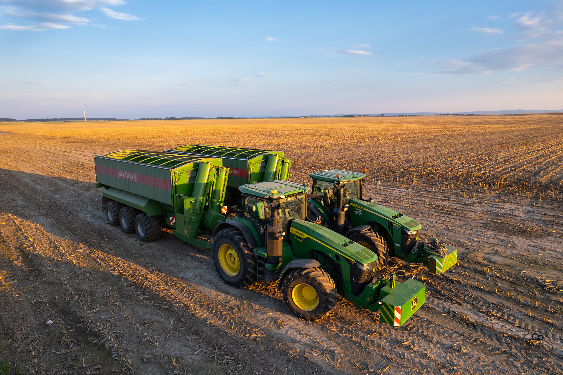 Dwa ciągniki John Deere z przyczepami przeładowczymi – zdjęcie z drona