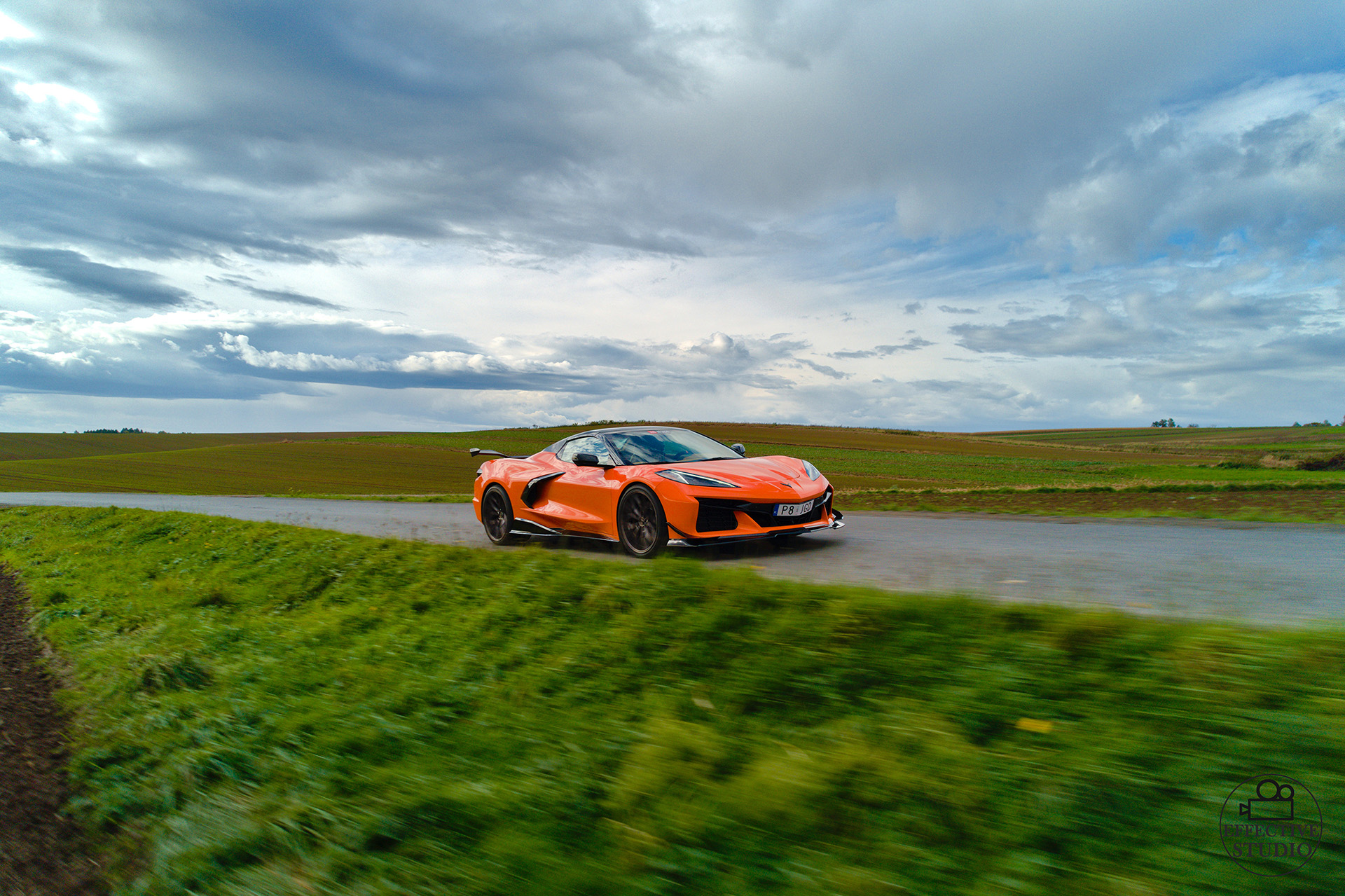 Pomarańczowy Chevrolet Corvette C8 jadący drogą, zdjęcia reklamowe wykonane dronem dla firmy sprzedającej części tuningowe JGD Attack.