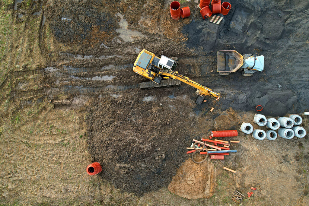 Koparka podczas pracy na placu budowy, uchwycona z lotu drona. Inspekcje i reklama dronem